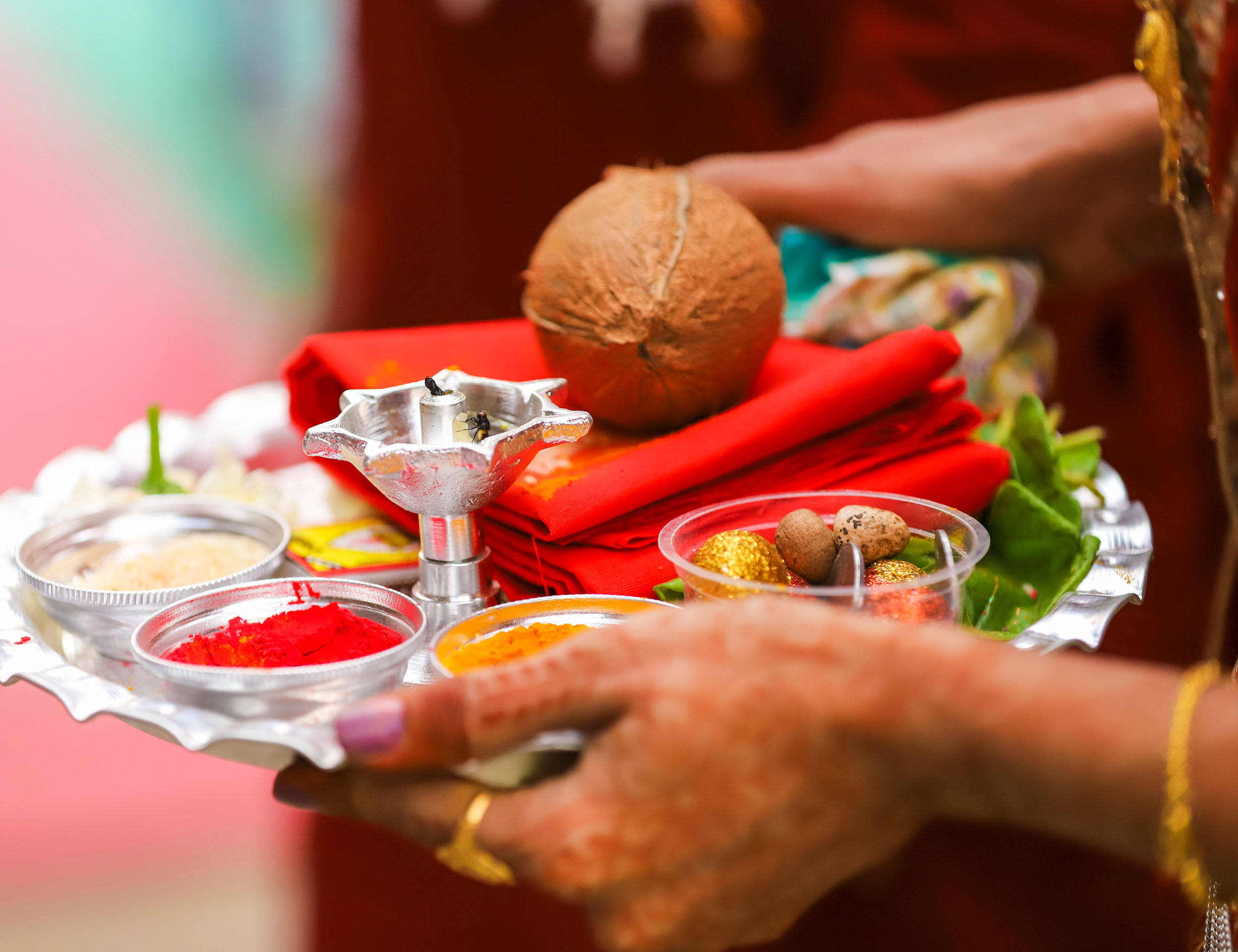 Close-up of traditional pooja thali with coconut, sindoor, turmeric, diya, and sacred items used in rituals